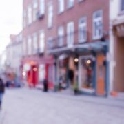 Vue floue d’une rue commerçante animée avec passants et devantures de boutiques