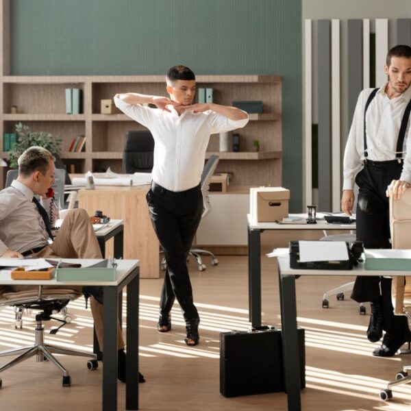 Trois collègues déplacent des bureaux pour réorganiser l’espace de travail et améliorer le confort en été.