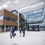Cadres se dirigeant vers un immeuble de bureaux moderne en verre et bois